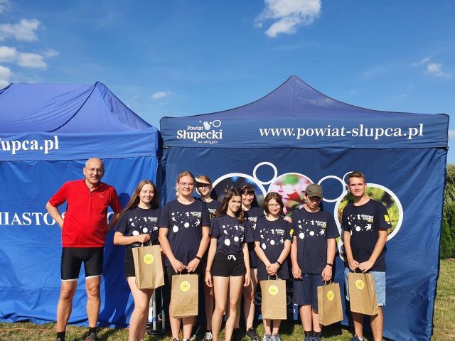 na pierwszym planie 9 osób , w tle namiot