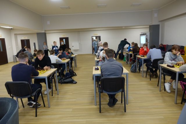 27 zawodników siedzących przy stolikach