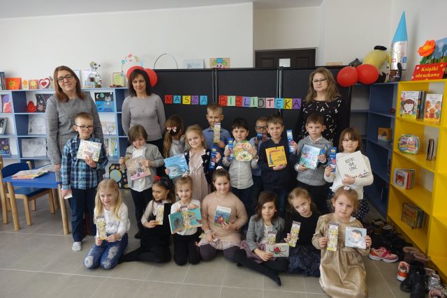 z przodu siedzą dzieci, za nimi stoją dzieci, a za nimi stoją trzy osoby dorosłe
