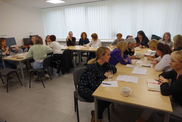 Uczestnicy szkolenia siedzą przy stołach