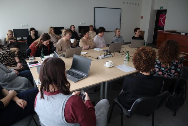 uczestnicy szkolenie siedzą przy stolikach i pracują na laptopach