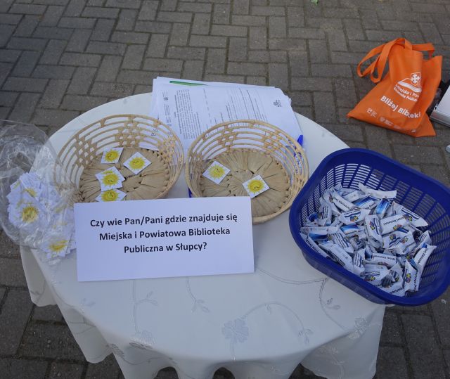 Na stoliku pokrytym białym obrusem w koszyczku karteczki ze słoneczkami i cukierki krówki oraz ankiety