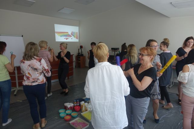 uczestnicy szkolenia na stojąco bawią się w papier, nożyce