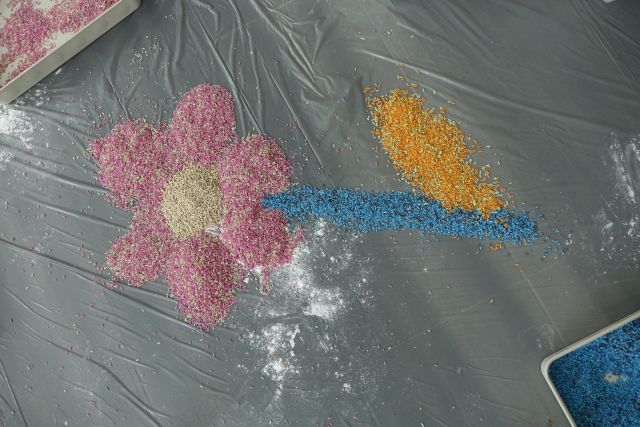 na siwej podłodze usypany z kolorowego ryżu kwiatek