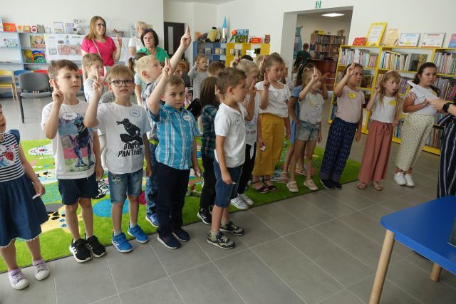 dzieci stoją z podniesionymi do góry rękoma