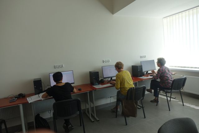 brzy brązowych biurkach przed komputerami siedzą tyłem trzy kobiety