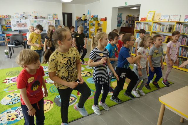 na zielonym dywanie dzieci stoją i podnoszą nogi