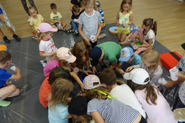 na czarnej folii dzieci nachylone nabierają ziemię