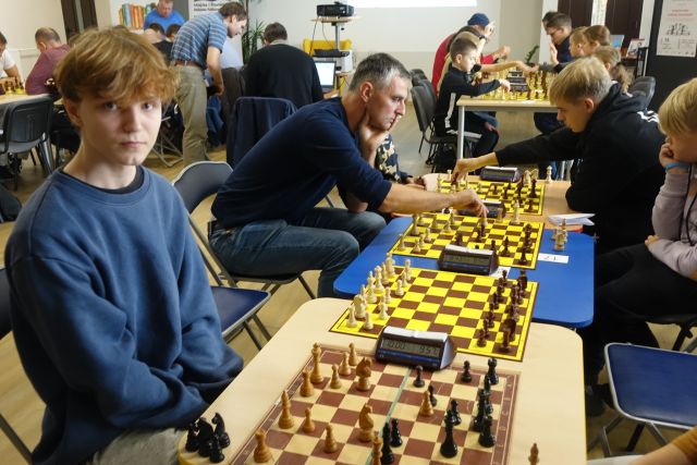 uczestnicy turnieju siedzą przy stolikach i grają w szachy