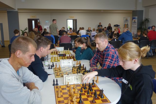 uczestnicy turnieju siedzą przy stolikach i grają w szachy