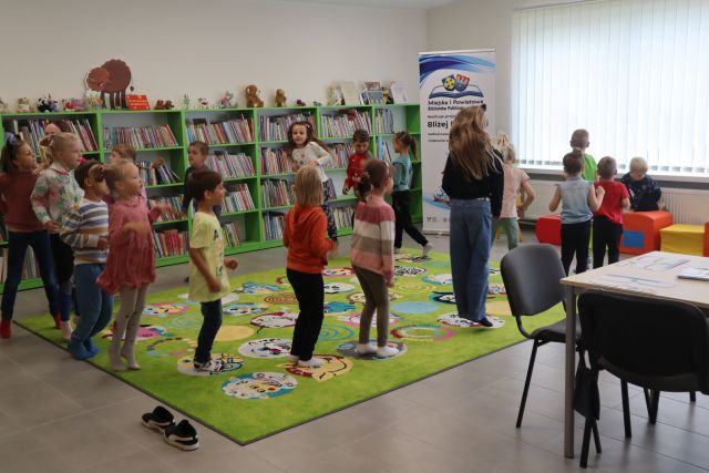 dzieci stoją na zielonym dywanie