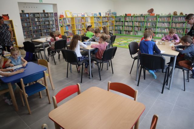 dzieci siedzą przy stolikacj i malują na kartkach