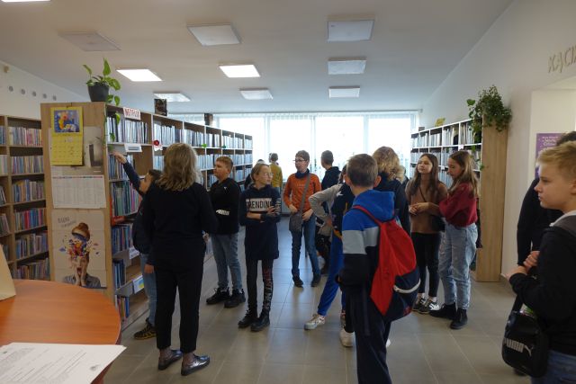 młodzież stoi przed regałami z książkami