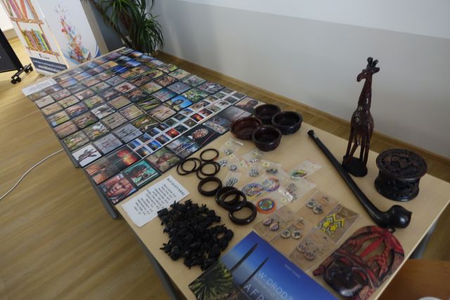 na stole leżą pocztówki i inne bibeloty, jak monety, breloki, znaczki