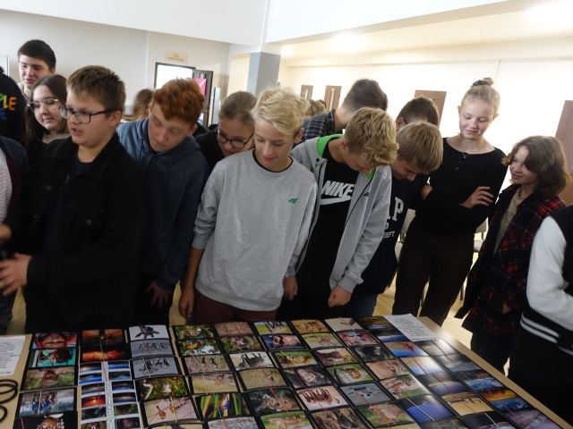 uczestnicy spotkania stoją przed stołęm z widokówkami i pamiątkami z Afryki