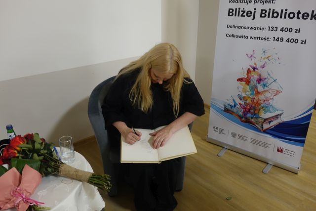 kobieta w czarnym kombinezonie trzyma bukiet czerwonych róż