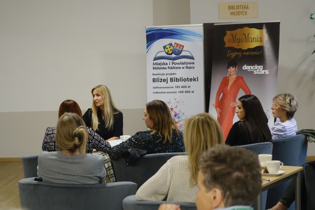 kobiety siedzą w siwych fotelach przy stolikach