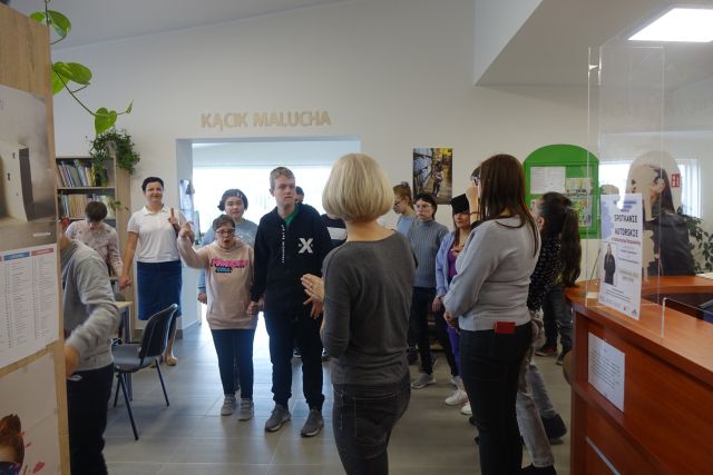 młodzież stoi przed regałami z książkami