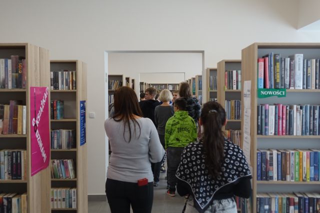 młodzież idzie pomiędzy regałąmi z książkami