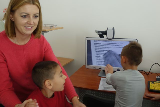 chłopiec w siwej bluzie, kobieta w różowej bluzie i chłopiec w czerwonej bluzce