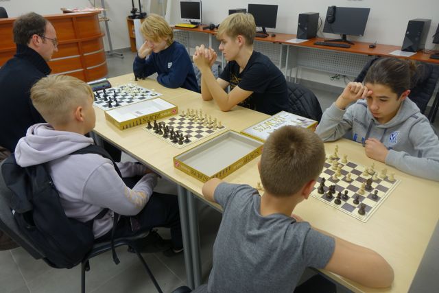 uczestnicy klubu szachowego grają w szachy przy stołach