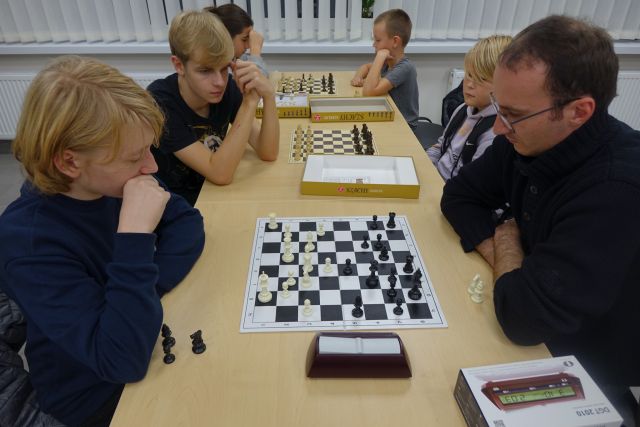 uczestnicy klubu grają w szachy przy stołach