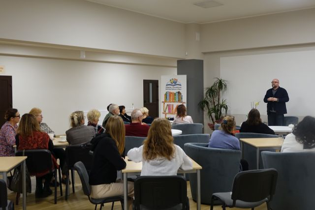 uczestnicy spotkania siedzą na fotelach przy stolikach