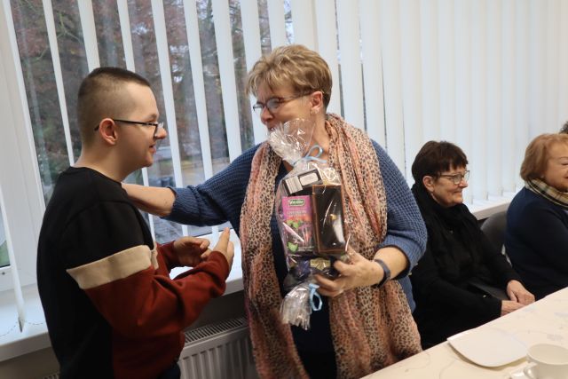 kobieta w niebieskim swetrze przyjmuje prezent od chłopca