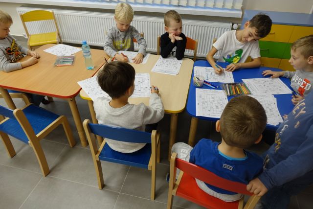 przy stołach siedzą dzieci i rozwiązują rebusy