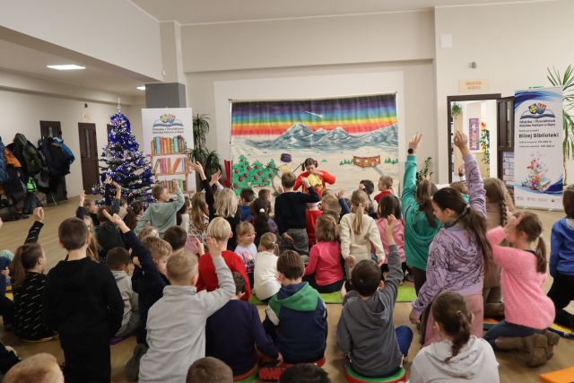 dzieci siedzą na podłodze i oglądają spektakl