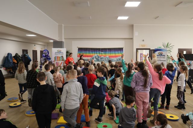 dzieci stoją przed kobietą w czerwonym swetrze i kobietą przebraną za łosia