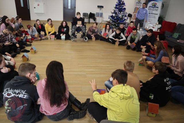 uczestnicy warsztatów siedzą w kole na podłodze