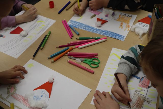 na stole leżą mikołąje wykonane z kartek i waty oraz kredki