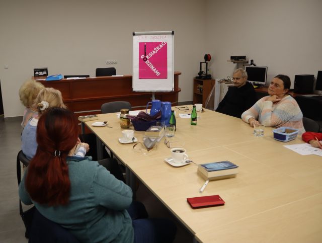 5 kobiet siedzi przy stole i dyskutuje, w tle plakat z dkk oraz brązowe biurko