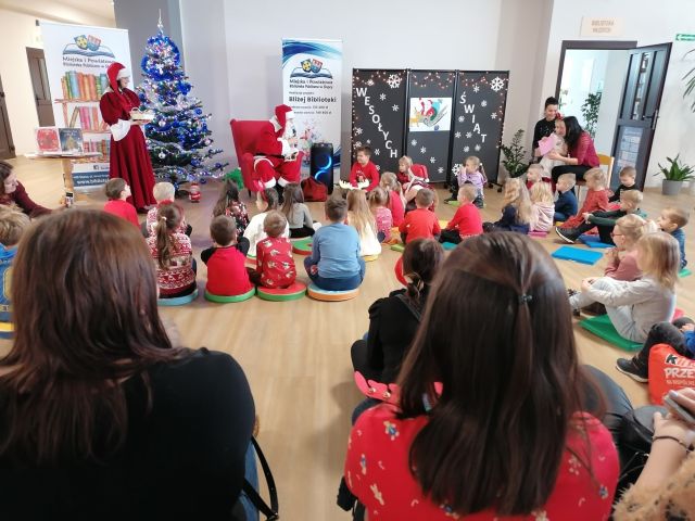 uczestnicy - dzieci siedzą na podłodze, przed nimi na czerwonym fotelu siedzi mikołaj