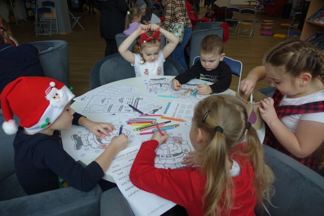 dzieci siedzą przy okrągłym stole i rozwiązują zagadki