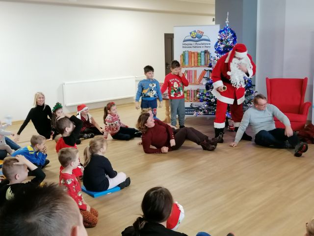 uczestnicy zabawy w rzepkę leżą na podłodze, przed nimi stoi mikołaj