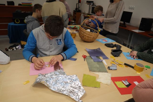 młodzież wykleja z różnych materiałów na kartkach kolorowych