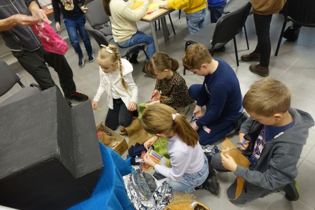 dzieci siedzą na podłodze i wybierają materiały