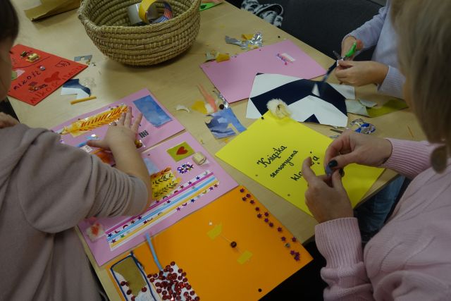 dzieci naklejają na kolorowe kartki różne kawałki materiałów