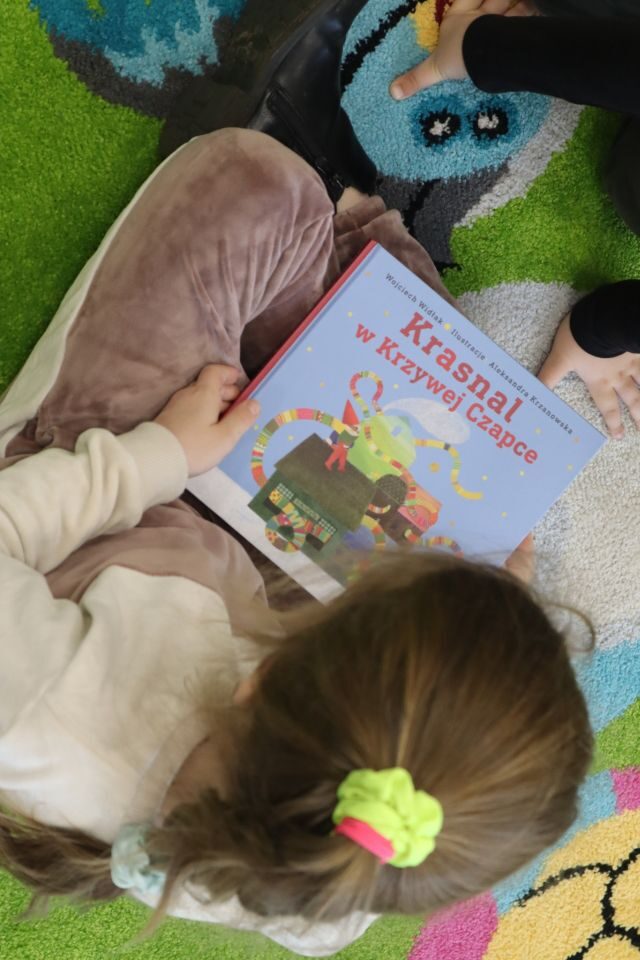 dzieci oglądają na dywanie książkę