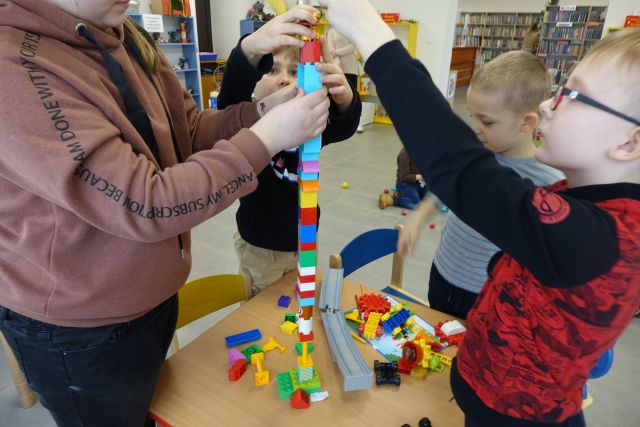 Dzieci budują wysoką wieżę z klocków LEGO