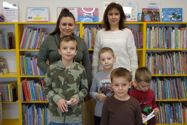 5 dzieci i dwie kobiety pozują do zdjęcia, w tle regały z książkami