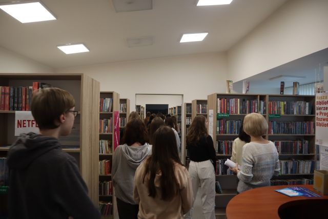 młodzież spaceruje pomiędzy regałami z książkami