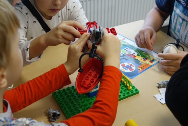 dzieci układają modele z klocków LEGO
