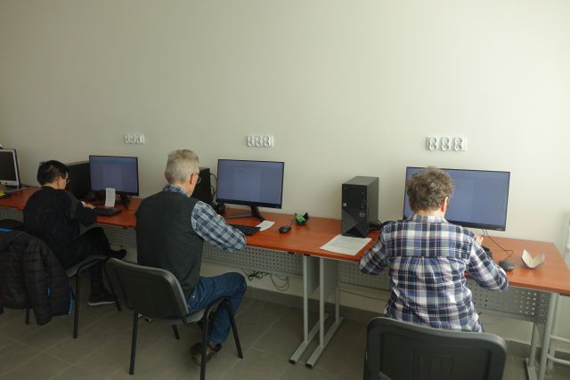 mężczyzna i dwie kobiety siedzą przy biurkach z komputerami