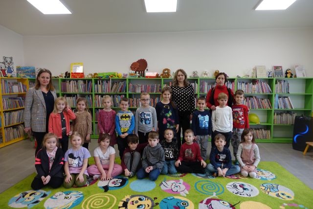 dzieci i 3 kobiety pozują do zdjęcia, w tle regały z książkami