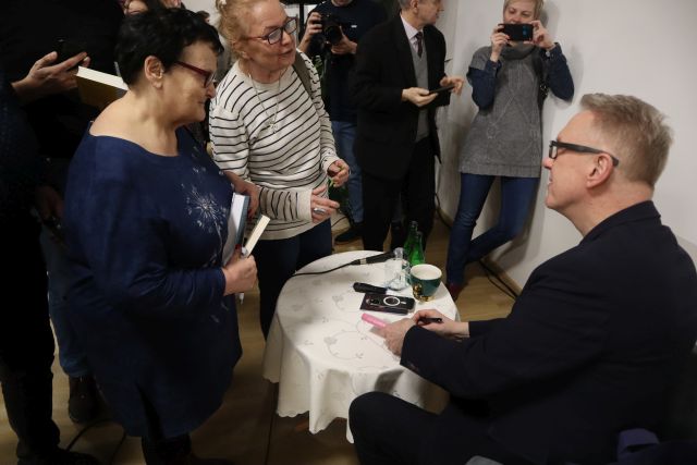 mężczyzna siedzący na fotelu rozmawia z uczestniczkami spotkania stojącymi przed nim