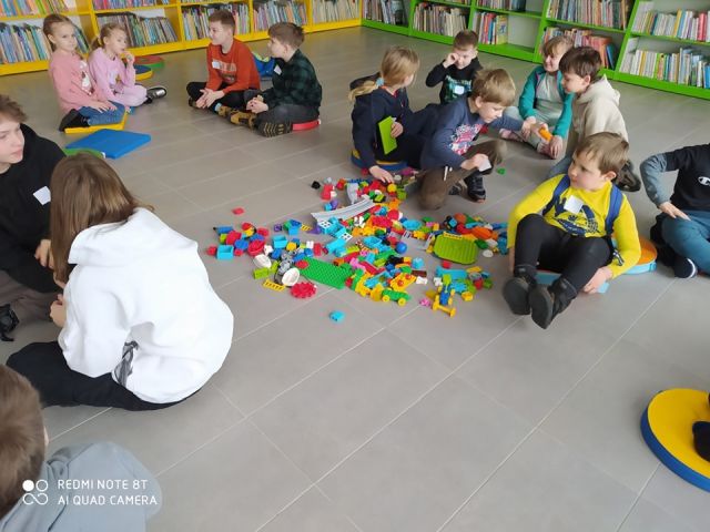 rozsypane na podłodze klocki, a wokół nich dzieci