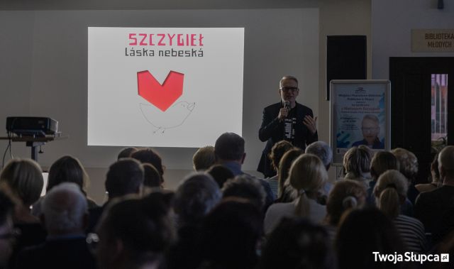 uczestnicy spotkania siedzący tyłem do aparatu, a przodem do autora